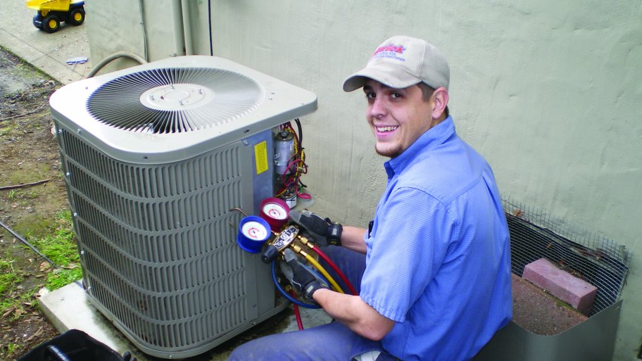 HVAC technician tests an air conditioner. HVAC technician inspects air conditioner.